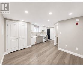 A spacious kitchen with white cabinets and a wooden floor.