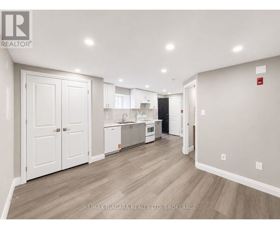 A spacious kitchen with white cabinets and a wooden floor.