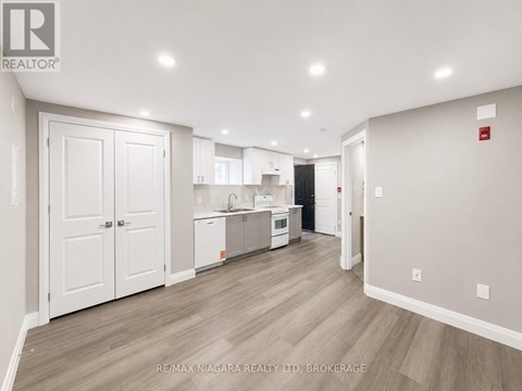 A spacious kitchen with white cabinets and a wooden floor.