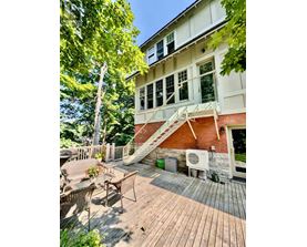 A wooden deck with a white table and chairs is in front of a house.