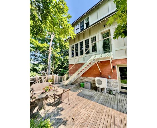 A wooden deck with a white table and chairs is in front of a house.