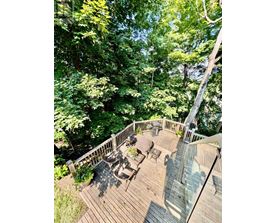 A wooden deck with a table and chairs surrounded by trees.