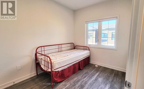 A bedroom with a red metal bed frame and a window.