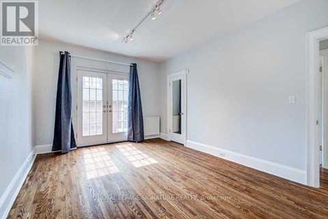 A room with wooden flooring and a large window with curtains.