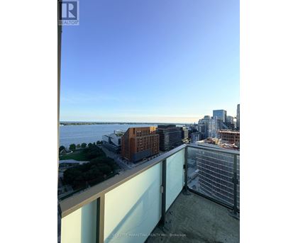 A balcony overlooks a cityscape with buildings and a body of water.