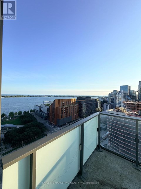 A balcony overlooks a cityscape with buildings and a body of water.