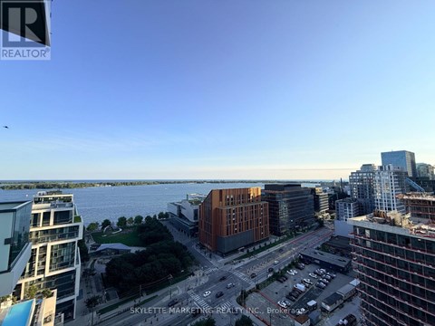 A cityscape with buildings and a body of water in the distance.