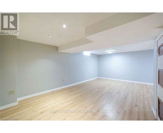 A spacious room with wooden flooring and white walls.
