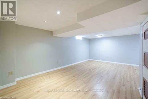 A spacious room with wooden flooring and white walls.