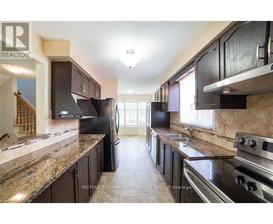 A kitchen with dark brown cabinets and granite countertops.