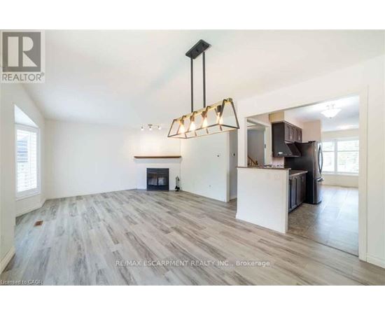 A spacious living room with a fireplace and a modern chandelier.