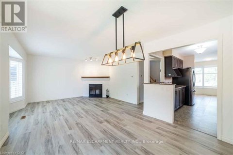 A spacious living room with a fireplace and a modern chandelier.