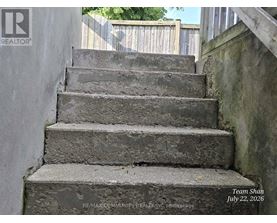 A set of concrete stairs with a wooden railing on the right side.