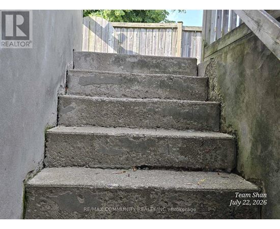 A set of concrete stairs with a wooden railing on the right side.