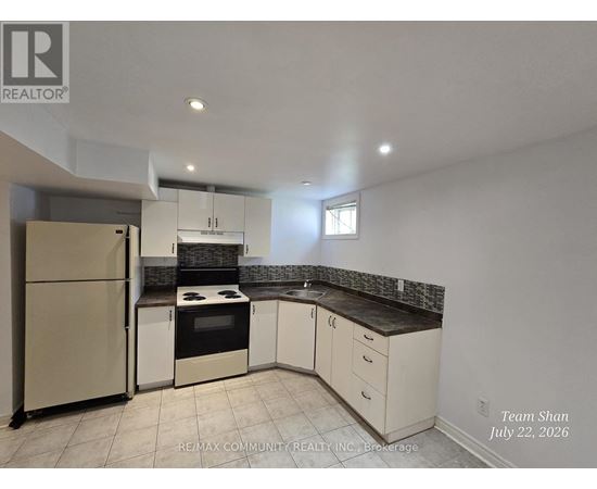 A kitchen with white cabinets and a refrigerator.