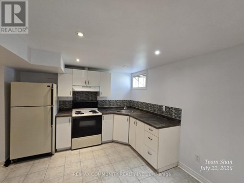 A kitchen with white cabinets and a refrigerator.