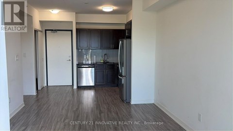 A kitchen area with a refrigerator, sink, and cabinets.