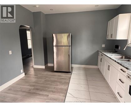 A kitchen with a stainless steel refrigerator and white cabinets.