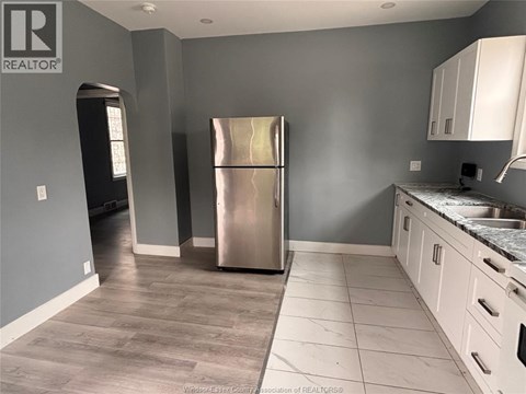 A kitchen with a stainless steel refrigerator and white cabinets.