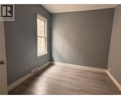 A room with a window and wooden flooring.