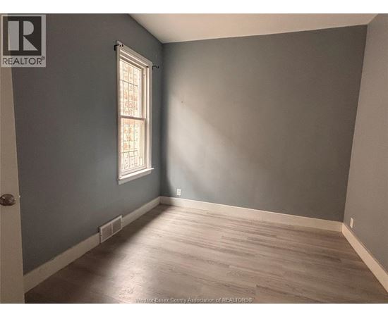A room with a window and wooden flooring.