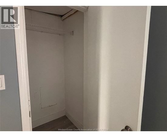 A small, empty room with a door on the left and a wall on the right.