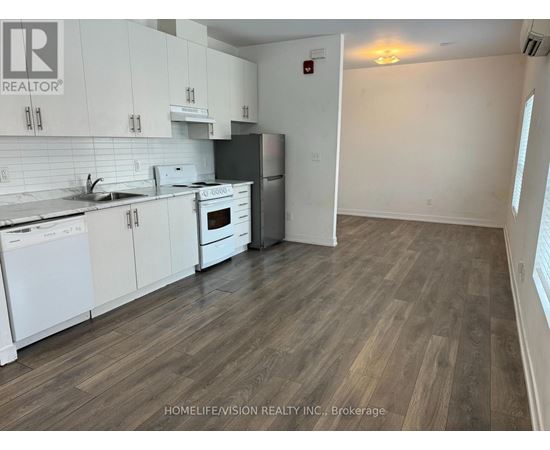 A kitchen with white cabinets and a wooden floor.