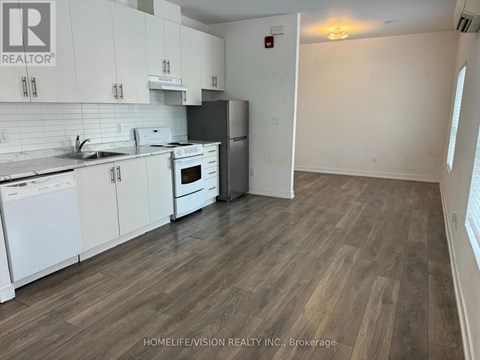 A kitchen with white cabinets and a wooden floor.