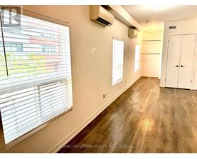 A room with wooden flooring and a window with blinds.