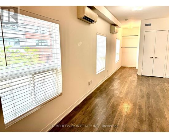 A room with wooden flooring and a window with blinds.