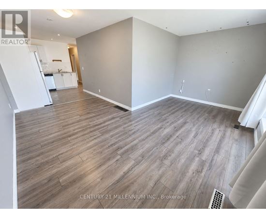 A spacious room with wooden flooring and white walls.