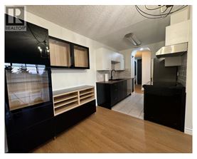 A modern kitchen with black appliances and wooden floors.