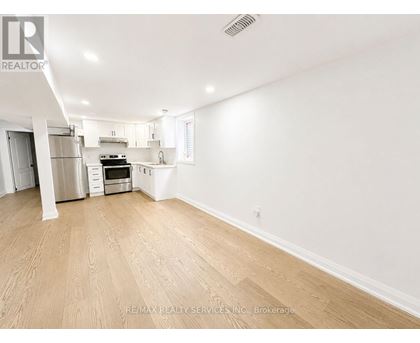 A spacious room with wooden flooring and white walls.