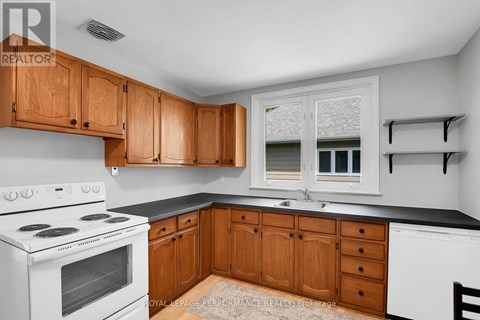 A kitchen with wooden cabinets and a white stove top oven.