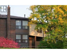 A brick building with a chimney and a tree with yellow leaves.
