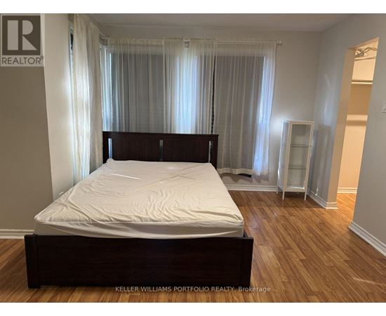 A bedroom with a large bed and wooden floors.