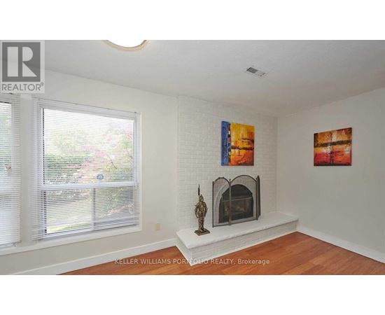 A living room with a fireplace and two paintings on the wall.