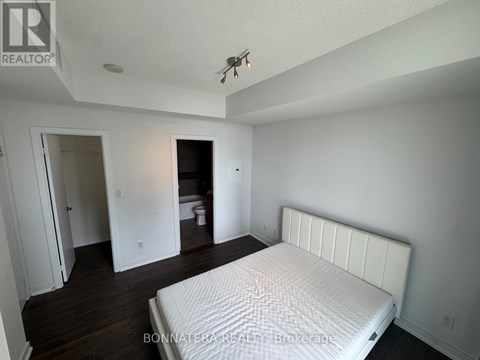 A bedroom with a large bed and a toilet visible through the door.