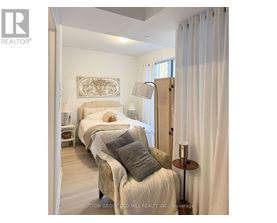 A bedroom with two beds and a nightstand with a lamp.