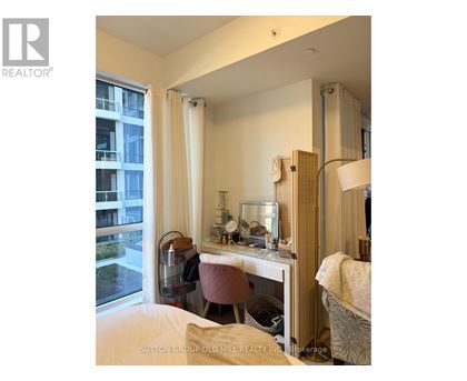 A bedroom with a desk and chair in front of a window.