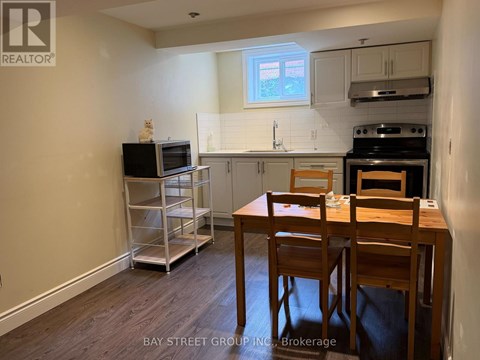 A kitchen with a table and chairs in the foreground and a microwave on the counter.