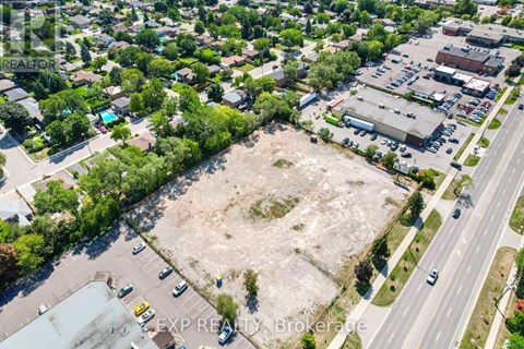 An aerial view of a large empty lot surrounded by buildings and a road.