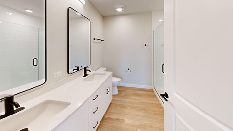 A white bathroom with a sink, mirror, and toilet.