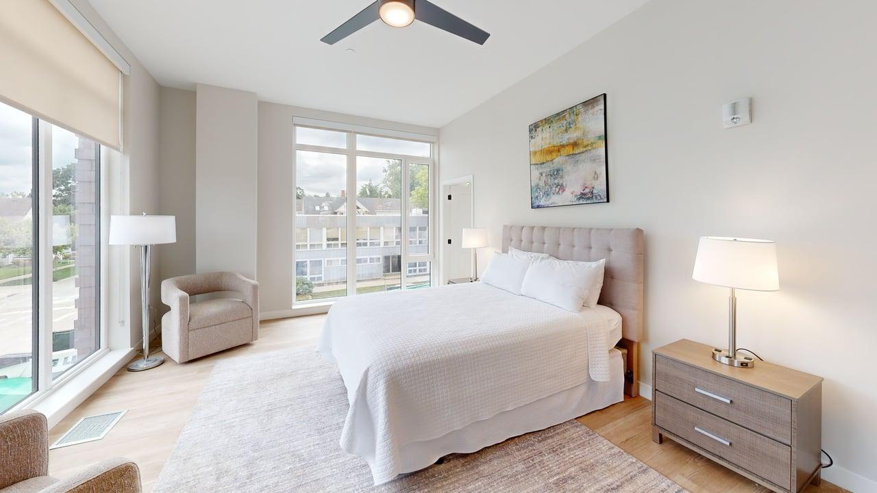 A bedroom with a large bed, a chair, and a ceiling fan.