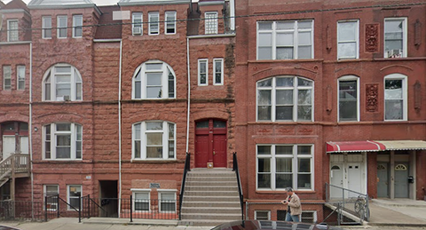 A red brick building with a woman walking in front.