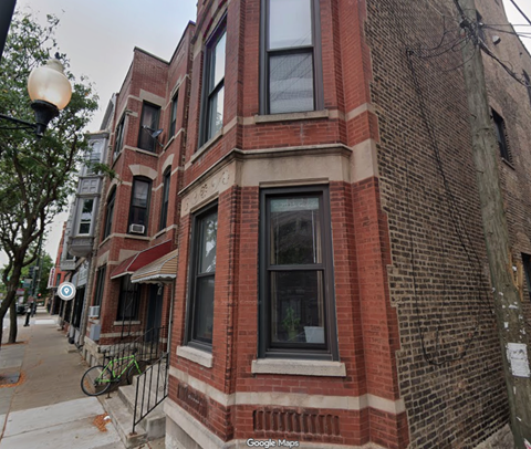 A street view of a red brick building with a bicycle parked on the sidewalk.