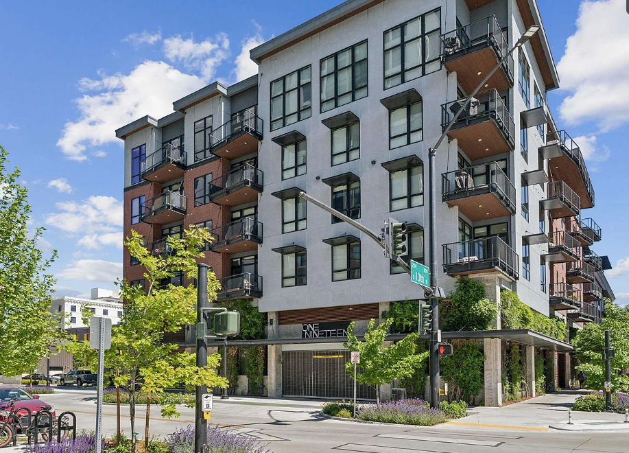 A modern apartment building with balconies and a street in front.