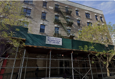 A building with a green construction tarp on the side.