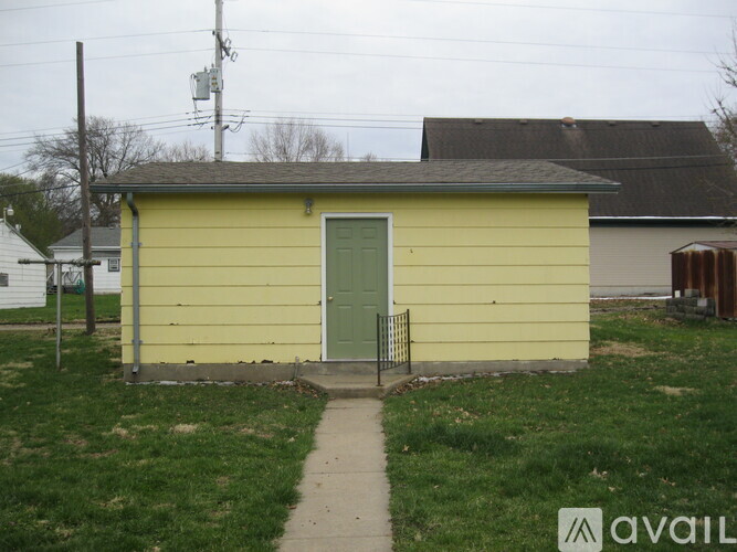 A small yellow building with a green door and a metal gate.