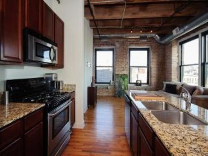 A kitchen with dark wood cabinets and a granite countertop.
